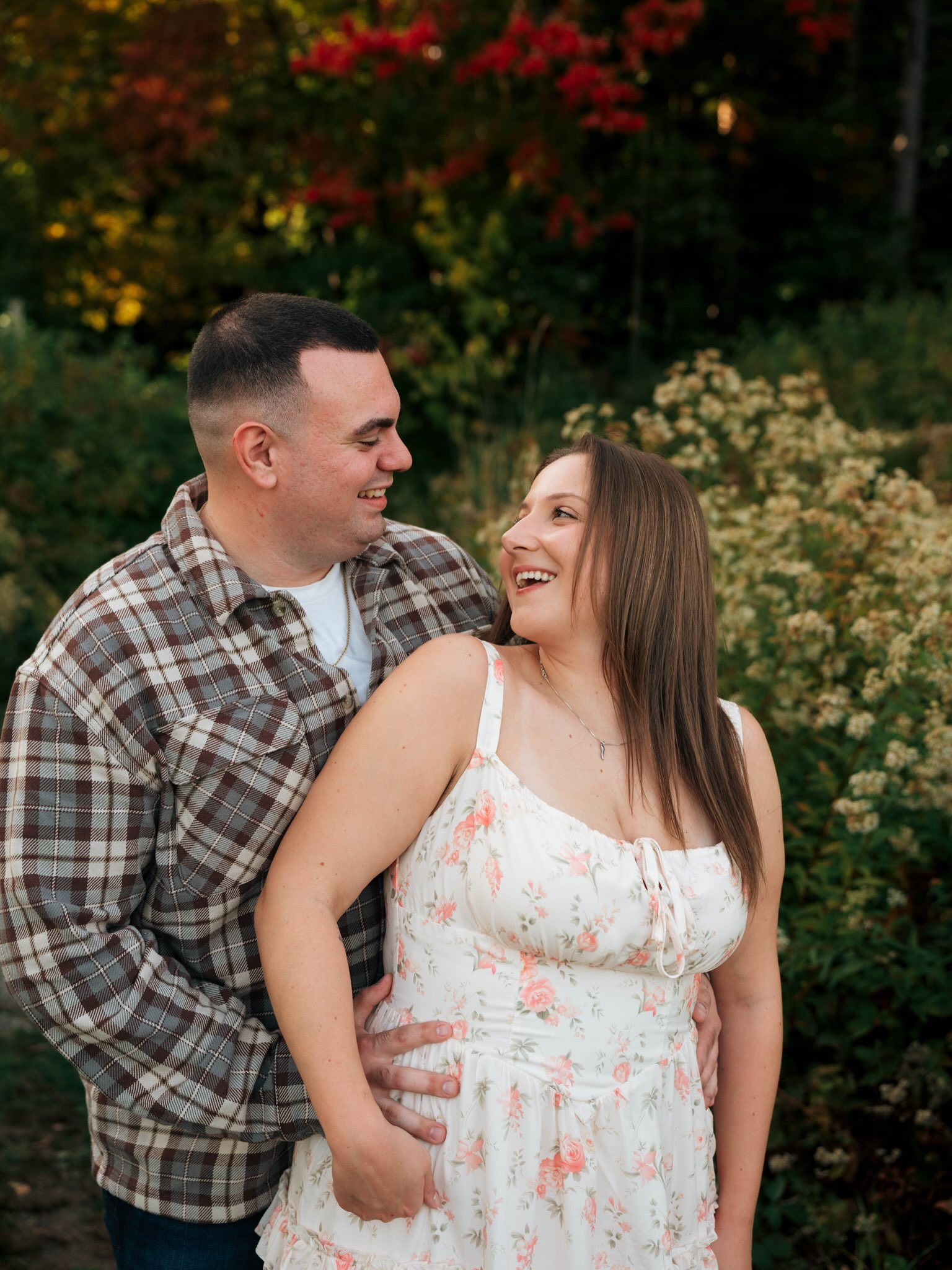 John and Erica laughing together among autumn flowers
